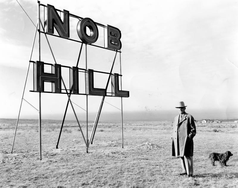 D. K. B. Sellers and dog stand beside the Nob Hill sign