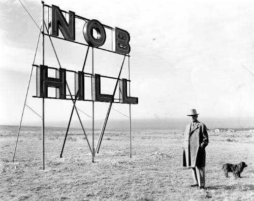 D. K. B. Sellers and dog stand beside the Nob Hill sign