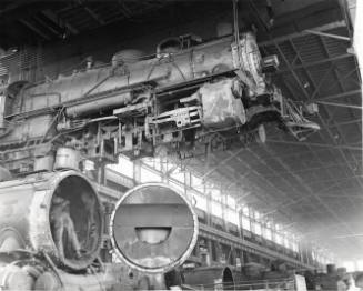 A locomotive is suspended above the floor at the AT&SF Railroad shop