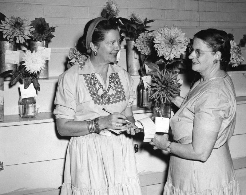 State Fair Flower Show competitors stand in front of many vases with flowers