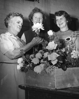 Chairwomen of local garden clubs at the Flower Show admire a flower arrangement