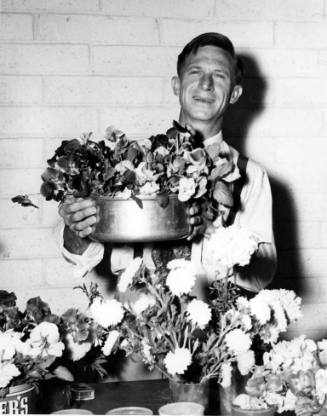 John Pulliam holds up a metal bowl of pansies at the floriculture exhibit