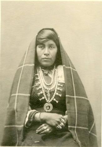 Isleta woman seated and wearing a shawl on her head