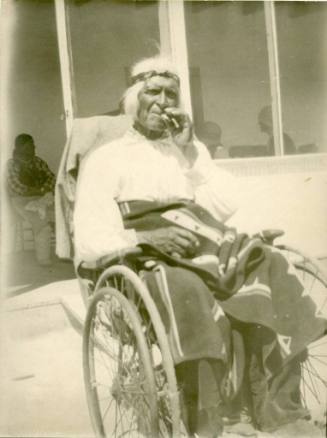 Elderly Isleta man in wheelchair smoking cigarette