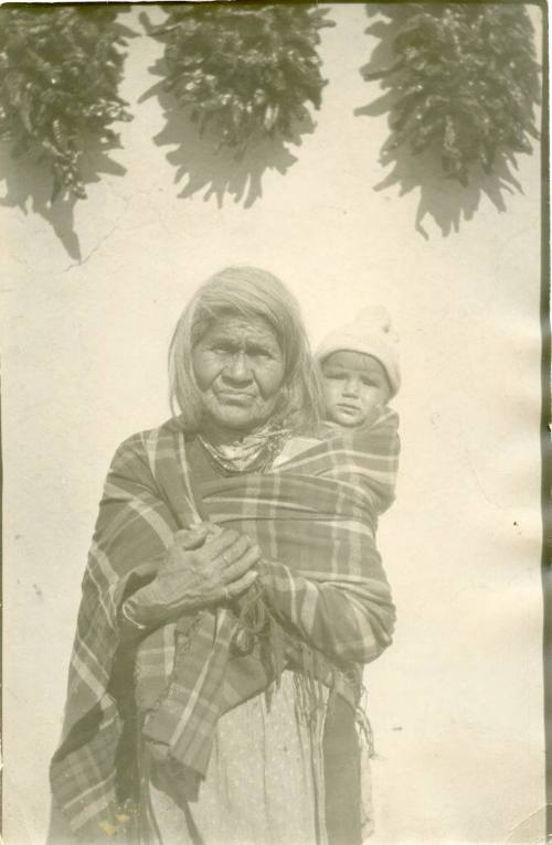 Elderly Isleta woman with a child on her back