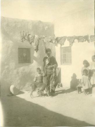 An Isleta man stands outside with a child and a dog