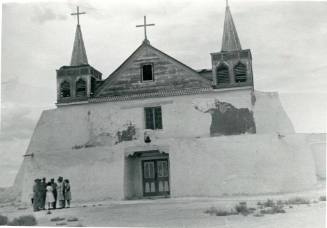A group of people in front of the Isleta Pueblo church