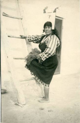 Native American woman stepping on ladder, holding pine boughs