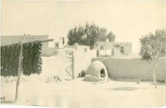 Adobe houses, horno, and ristras hanging in a yard in Isleta Pueblo