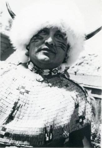 Native American man wearing a headdress with fur and horns