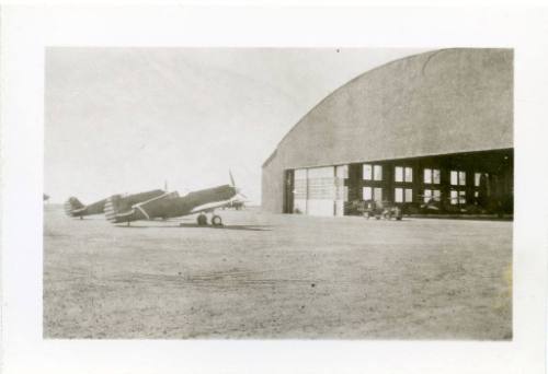 Two Curtiss P-40 Warhawk aircraft outside of a hangar at Albquerque Airport