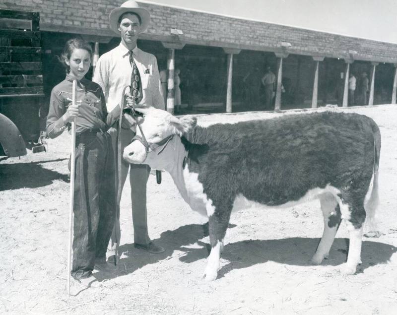 An unidentified young handler and a man stand with a Champion Hereford Female