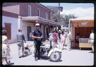 A policeman stands beside his motorcycle in Old Town