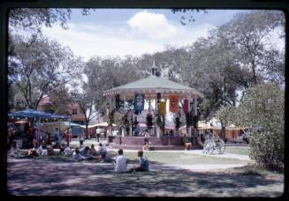 People sit on the grass around the gazebo in Old Town