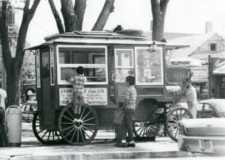 A family stands at a popcorn wagon parked in the Old Town Plaza
