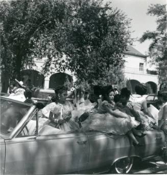 A group of women speak to each other near a convertible