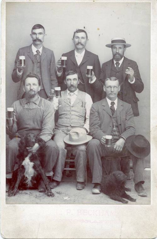 Portrait of six unidentified men holding mugs of beer