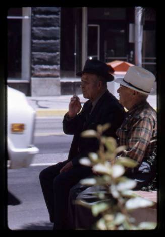 Two men sit on a brick wall along Central Avenue