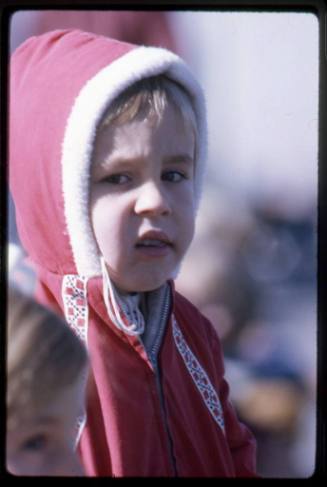 A child wears a red coat at the UNM Homecoming parade