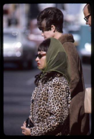 A woman in an animal-print coat waits to cross a street in downtown Albuquerque
