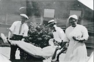 Rebecka Miller and two men carry a third man at the Santa Fe Railroad Hospital