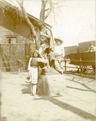 Two Native American children pose with a Native American statue