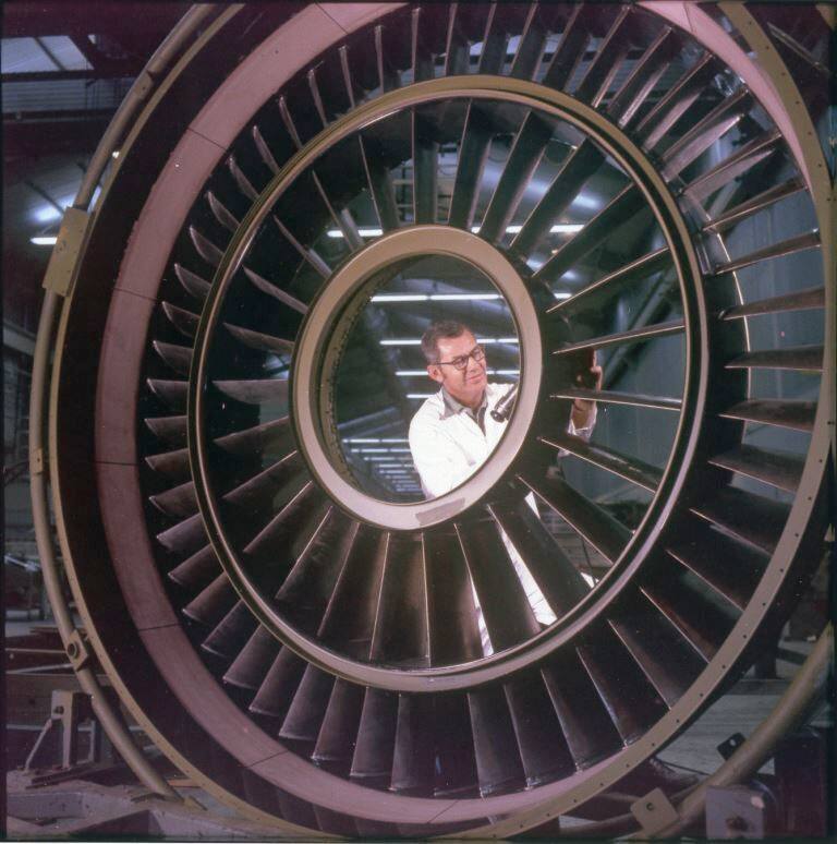 A General Electric employee works on a part for a jet engine