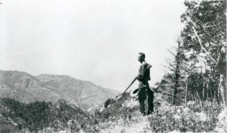 Man standing with a shotgun looking over the landscape