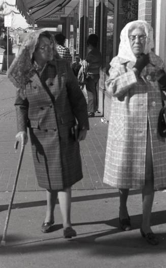 Two women walking down a sidewalk