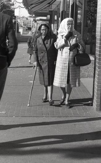 Two women walking down a sidewalk