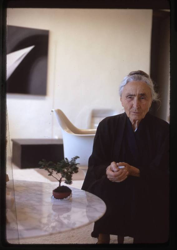 Georgia O'Keeffe at table, painting in background