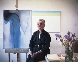 Georgia O'Keeffe sitting by easel painting