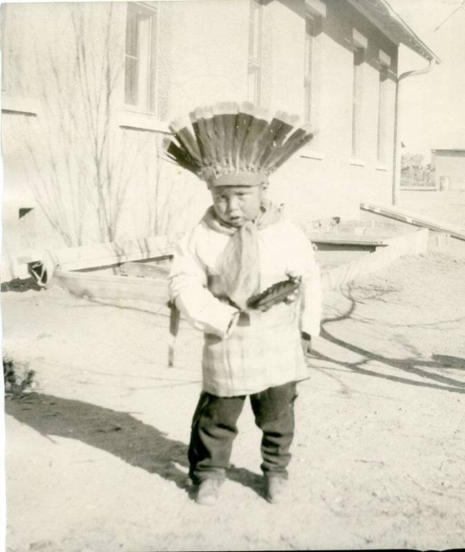 Native American boy wearing a headdress and holding a feather
