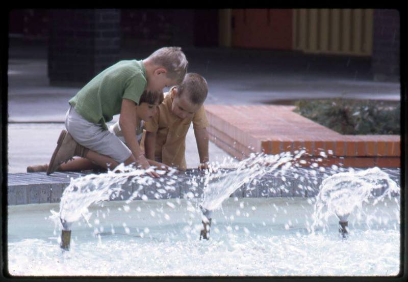 Three boys play near the fountain at Coronado Center