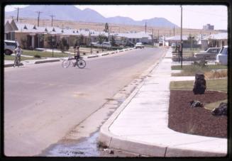 Two children ride bikes on a street