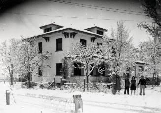 Four people stand in the snow in front of the Bottger Mansion