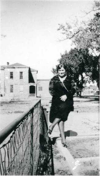 Minnie May Miller stands beside a fence